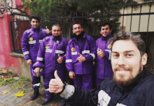 a man giving a thumbs up with a group of men wearing purple jackets