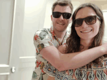 a man and a woman wearing sunglasses are hugging and smiling