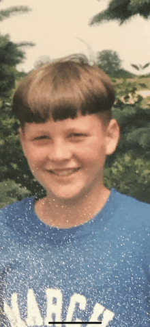 a young boy wearing a blue shirt that says march smiles for the camera