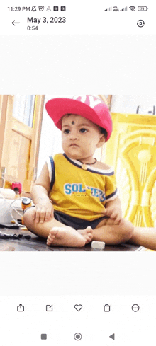 a baby wearing a red hat and a yellow shirt with soldiers on it