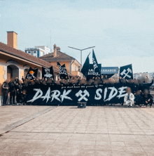 a large group of people holding a banner that says dark side