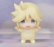 a small figurine of a baby with yellow hair and blue eyes is standing on a table .