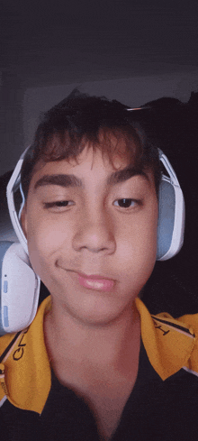 a young boy wearing headphones and a yellow shirt with the letter o on the collar