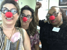 three women wearing clown noses and glasses are posing for a picture together