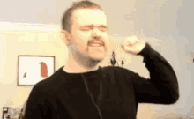 a man with a mustache is flexing his muscles while wearing headphones .