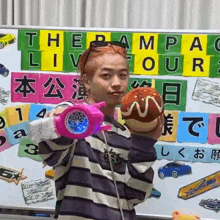 a girl is holding a toy gun and a donut in front of a white board with chinese writing on it .