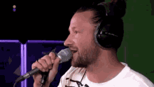 a man with a beard is singing into a microphone with headphones on .