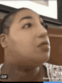 a woman with a shaved head is making a funny face in a gif .