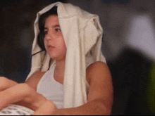 a girl wearing a white tank top with a white blanket draped over her head