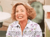 a woman is laughing and saying `` too funny '' while wearing a floral shirt .