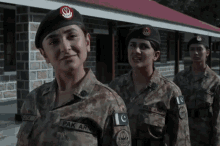 three female soldiers are standing in front of a building one of them has the name pak army on her uniform