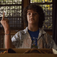 a young man with curly hair is giving the middle finger while sitting in a box .