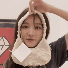 a woman wearing a black shirt with chinese writing on it holds a piece of fabric over her head