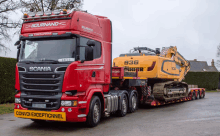 a red and black scania truck is carrying a yellow herr excavator