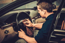 a man cleaning the steering wheel of his car with a cloth