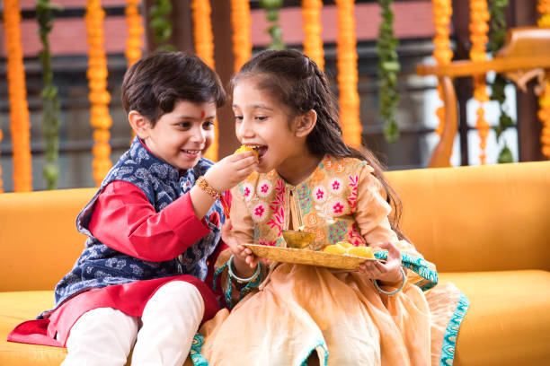 Boy feeding sweet food to his sister Little brother feeding sweet food to his sister on the occasion of Raksha Bandhan festival diwali kids stock pictures, royalty-free photos & images