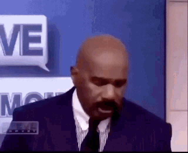 a bald man in a suit and tie is standing in front of a sign that says move .