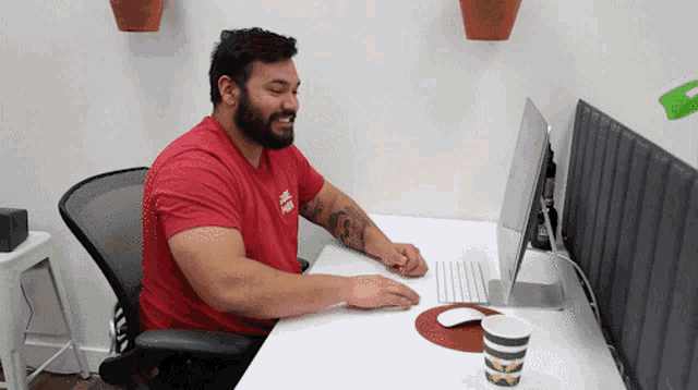 a man sitting at a desk with a red shirt on that says ' a few bucks ' on it