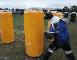 a man in a blue jacket is standing in front of a row of yellow cylinders that are covered in foam