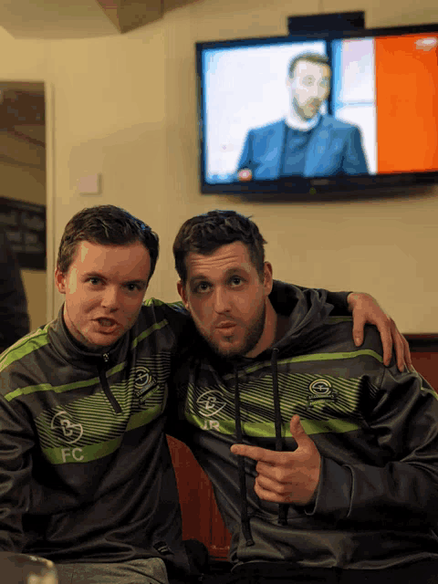 two men are posing for a picture with one wearing a sweatshirt that says fc