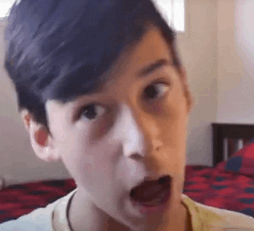 a young boy is making a funny face in a bedroom with his mouth open .