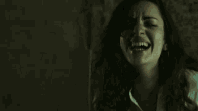 a woman is screaming with her mouth wide open in a dark room