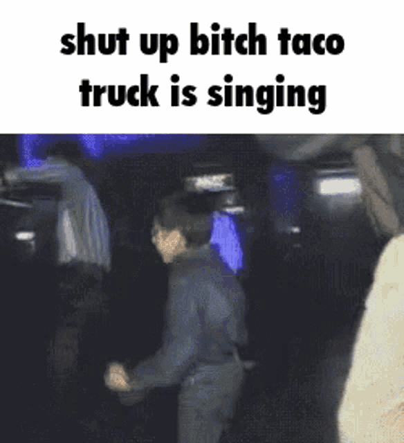 a man is dancing in a dark room with a caption that says shut up bitch taco truck is singing .