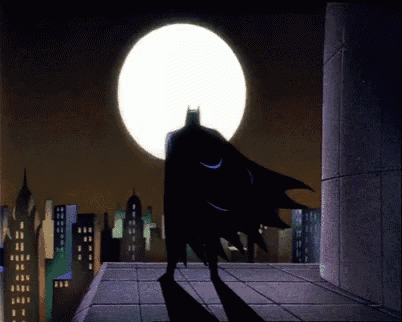 a silhouette of batman standing on a rooftop in front of a full moon