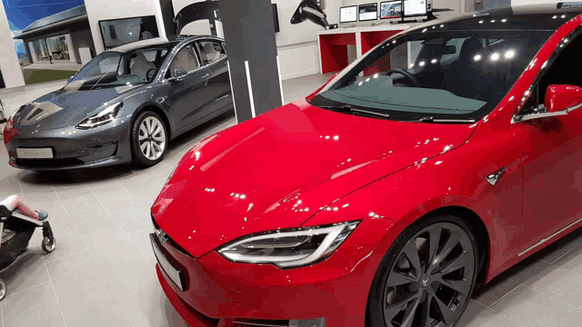 a red tesla model 3 is parked next to a gray model 3