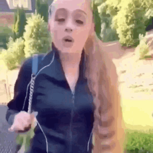 a woman with long blonde hair is wearing a black jacket and a backpack .