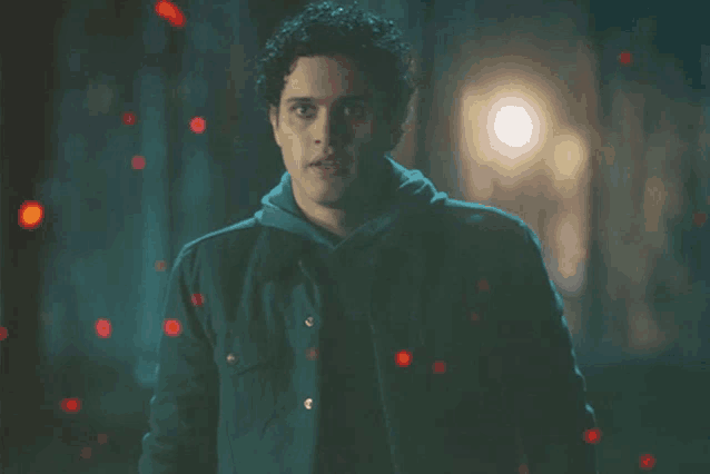 a man in a dark room with red lights coming out of his jacket