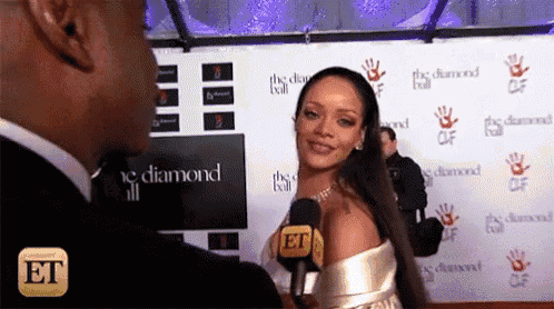 a woman in a white dress is being interviewed by a man on a red carpet with the word et on the bottom