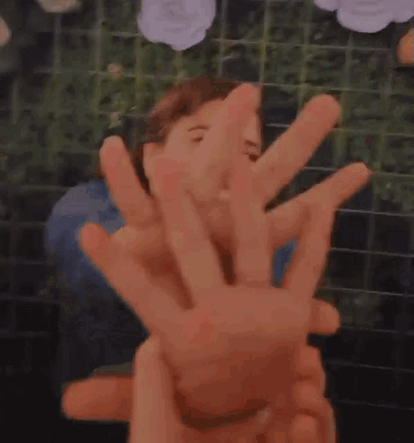 a close up of a person 's hands reaching out towards another person 's face .