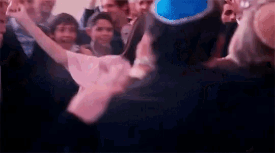 a group of people are dancing in a room with a blue hat on