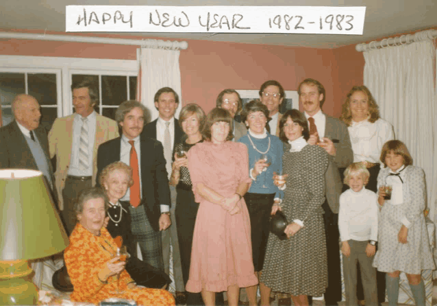 a group of people posing in front of a sign that says happy new year