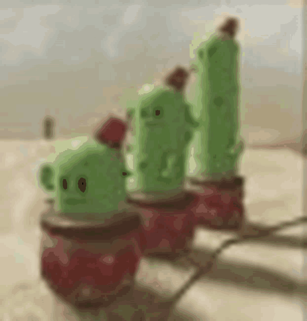 a row of green cactus figurines sitting on top of each other on a table .