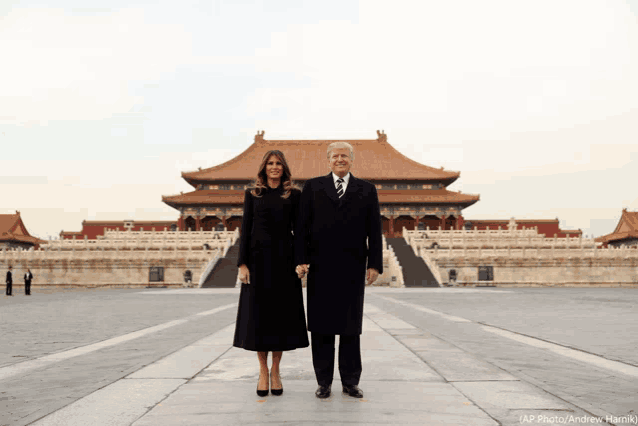 a man and a woman are standing in front of a chinese building