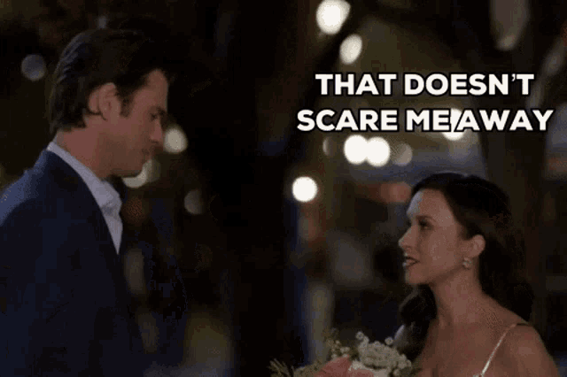 a man and a woman are looking at each other with the words that does n't scare me away behind them