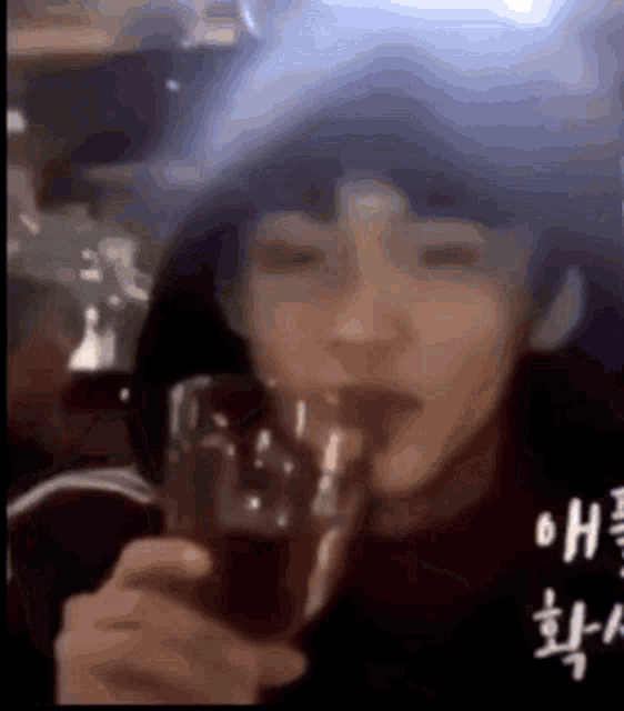 a man is drinking from a glass with a straw .