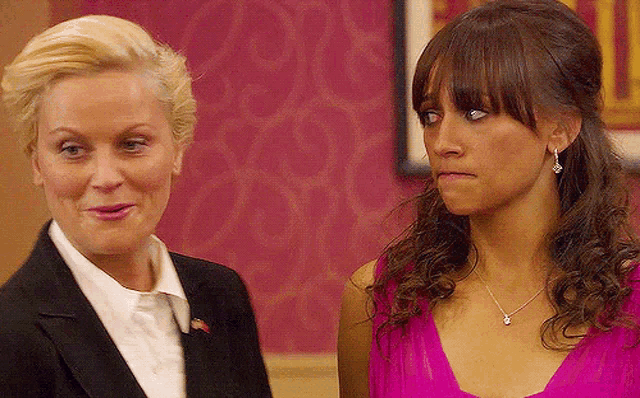a woman in a pink dress and a woman in a suit are standing next to each other