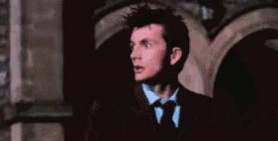 a man in a suit and tie is standing in front of a building and looking at something .