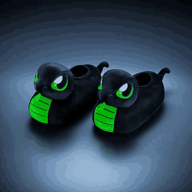 a pair of black slippers with green eyes and a green mouth