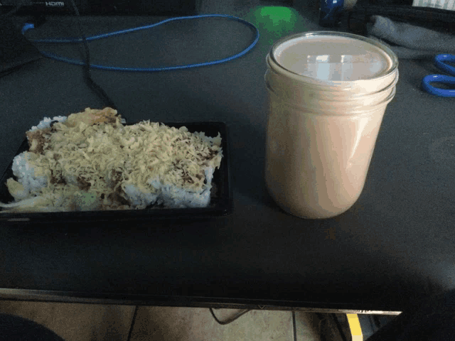 a jar of sauce sits on a table next to a tray of food