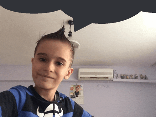 a young boy with a mohawk takes a selfie in a room