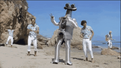 a group of men are standing on a beach and one of them is wearing a frog costume