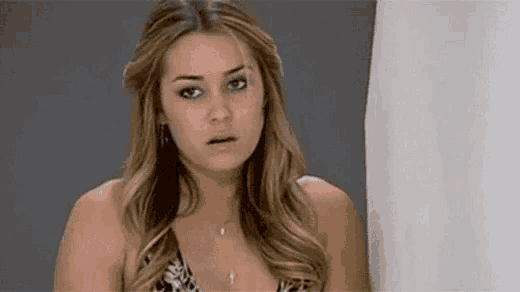 a woman in a bikini is standing in front of a shower curtain and making a surprised face .
