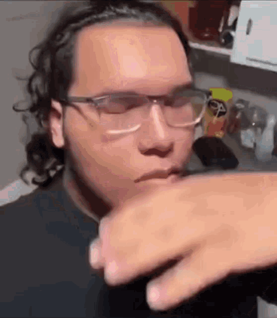 a man wearing glasses and a black shirt is eating something .