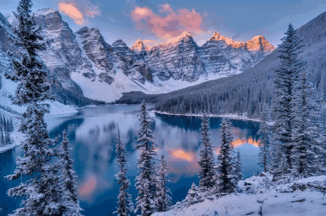 a lake surrounded by snow covered trees in the mountains