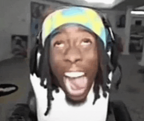 a man with dreadlocks wearing headphones and a headband is sticking his tongue out .