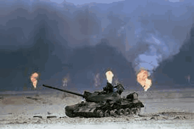 a military tank is driving through a field of fire .